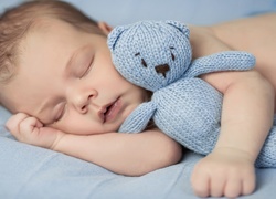 Śpiący niemowlak tuli niebieskiego misia