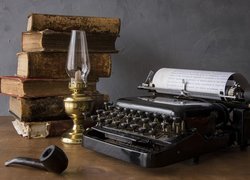 Stara maszyna do pisania obok książek i lampy