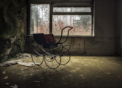 Stary dziecięcy wózek w zniszczonym pomieszczeniu