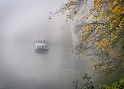 Statek wycieczkowy na zamglonym jeziorze obok skał