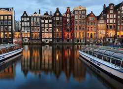 Statki na wodzie i budynki nad kanałem wodnym w Amsterdamie