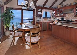 Stół z krzesłami ustawiony w kuchni z widokiem na morze