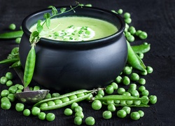 Strąki zielonego groszku obok miski z zupą