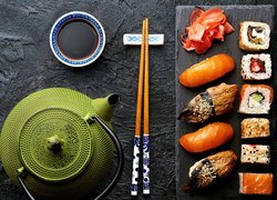 Sushi i pałeczki obok czajnika z herbatą