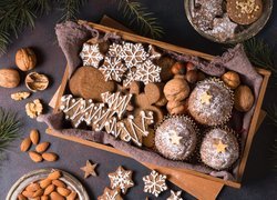 Świąteczne ciasteczka i orzechy na drewnianej tacy obok gałązek