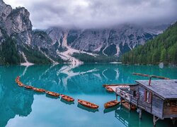 Szereg łodzi na jeziorze Lago di Braies i mgła nad Dolomitami