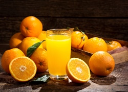 Szklanka soku obok skrzynki z pomarańczami