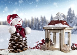 Szyszkowy bałwanek na śniegu i świąteczny lampion