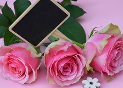 Tabliczka i różowe róże na różowym tle
