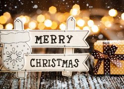 Tabliczka z napisem Merry Christmas obok prezentu