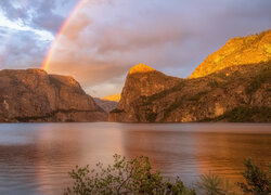 Tęcza nad rozświetlonymi górami i rzeką w Parku Narodowym Yosemite
