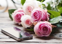 Telefon komórkowy obok róż