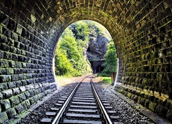 Tory w tunelu z widokiem na skały i drzewa