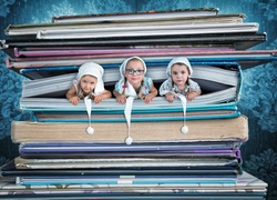 Trzy dziewczynki w czapkach wyglądają z książki