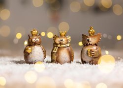 Trzy figurki sów w koronach na śniegu