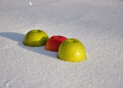 Trzy jabłka leżące w śniegu