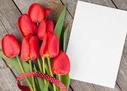 Tulipany położone na deskach obok kartki