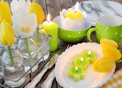 Tulipany w butelkach obok świeczek