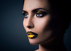 Twarz kobiety w żółto-czarnym makijażu