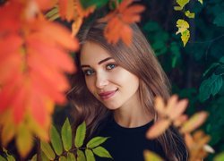 Uśmiechnięta dziewczyna w jesiennych liściach