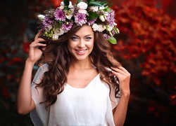 Uśmiechnięta dziewczyna w wianku z kwiatów na głowie