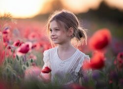 Uśmiechnięta dziewczynka wśród maków na polu
