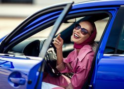 Uśmiechnięta kobieta w niebieskim samochodzie