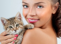 Uśmiechnięta kobieta z małym kotkiem na ramieniu