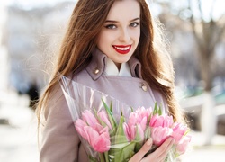 Uśmiechnięta kobieta z różowymi tulipanami