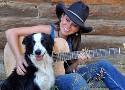 Uśmiechnięta piosenkarka Carin Mari z gitarą i psem border collie