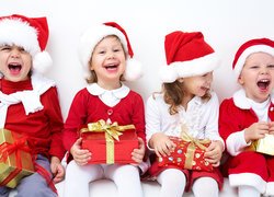 Uśmiechnięte dzieci w stroju Mikołaja z prezentami