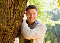 Uśmiechnięty mężczyzna obok drzewa