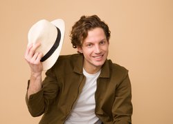 Uśmiechnięty mężczyzna z kapeluszem w ręce