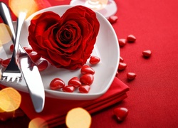 Walentynkowo nakryty stół z różą na talerzyku i serduszkami