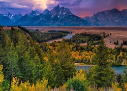 Widok na drzewa po obu brzegach rzeki i góry Teton Range w Parku Narodowym Grand Teton