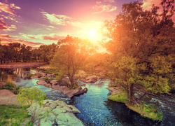 Widok na rzekę, drzewa i skały w świetle zachodzącego słońca