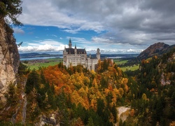 Widok na skały, drzewa i zamek Neuschwanstein w niemieckiej Bawarii