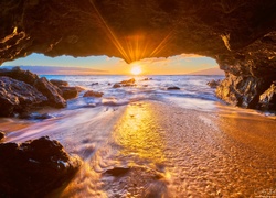 Widok na zachodzące słońce nad oceanem z jaskini na wybrzeżu Maui