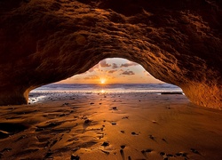 Widok z jaskini na morze i zachód słońca