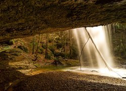 Widok z jaskini na wodospad spadający ze skały