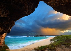 Widok z jaskini na zachmurzone niebo nad plażą na Karaibach