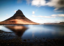 Widok z kamienistego brzegu na górę Kirkjufell w Islandii