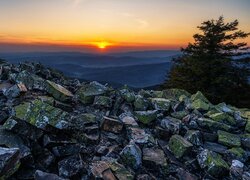 Widok z kamienistego wzgórza na zachód słońca nad górami