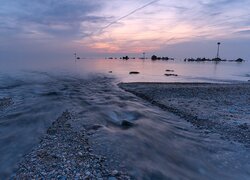 Widok z kamienistej plaży na wschód słońca nad morzem