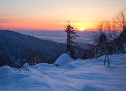 Widok z zaśnieżonego wzgórza na zachód słońca nad górami