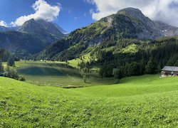 Widok z zielonej łąki na jezioro i góry