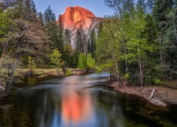 Widok znad rzeki Merced River na rozświetlony szczyt Half Dome