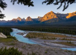 Widok znad rzeki na rozświetlone góry Canadian Rockies