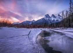 Widok znad zaśnieżonej rzeki na górę Three Sisters w Kanadzie