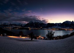 Wieczór nad jeziorem Thunersee i oświetlone domy w Oberhofen zimową porą